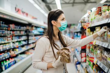 Shopping during an epidemic.Buyer wearing a protective mask.Nonperishable smart purchased household pantry groceries.Pandemic quarantine preparation.Dry goods and nutritional foods shopping.Expiration
