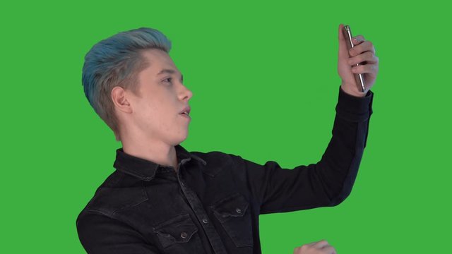 Young attractive man take a selfi looking at camera on green scren show like