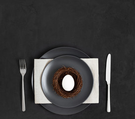 Easter minimal table setting with an egg nest on a black background.