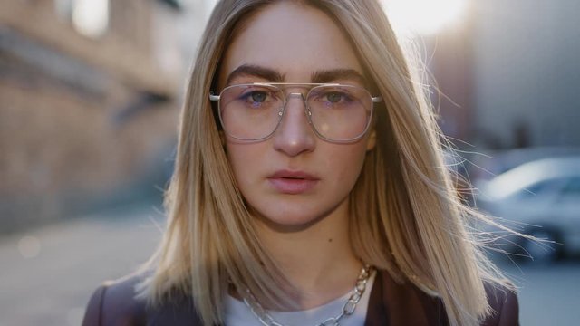 Close up portrait of beautiful european blonde woman in glasses looking to the camera spring sunny day sunlight outdoor slow motion