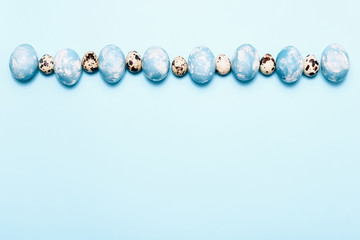 Stylish eggs with ombre blue marble stone effect in row on blue background