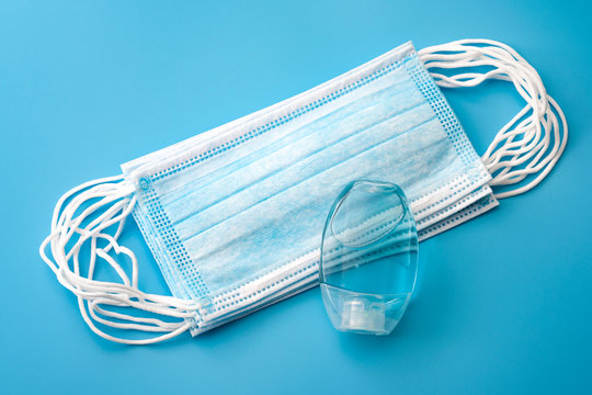 Infectious illness and influenza and corona virus germs concept with surgical masks for respiratory spread prevention and alcohol based hand sanitizer to rub hands with isolated on blue background