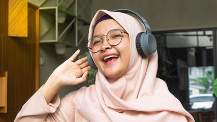 Hijab woman listens to music through headphones