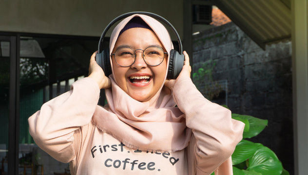 Hijab woman listens to music through headphones