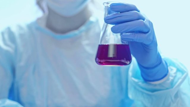 Covid-19 pandemia. Antigen development. Technician in gloves checking chemical reaction.