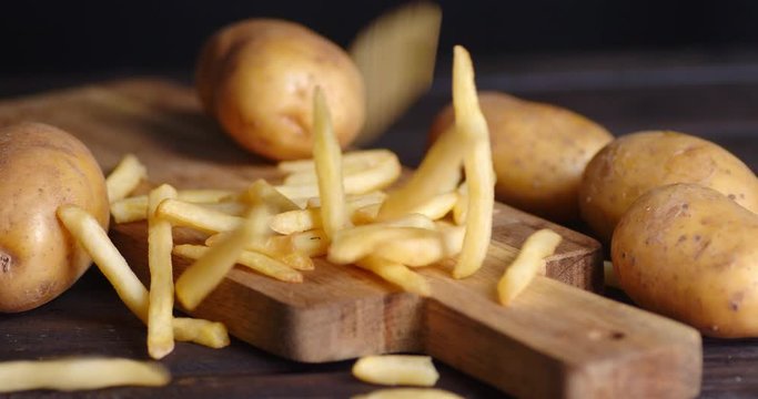 French fries drops on wooden cutting Board.