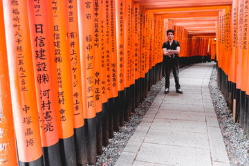 Traveler and torii gates path at Fushimi Inari taisha shrine, Kyoto