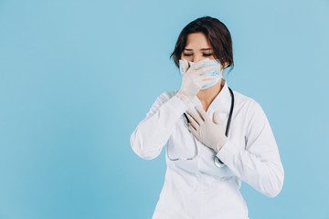 Symptoms of coronavirus. A female doctor holds a medical mask and coughs heavily