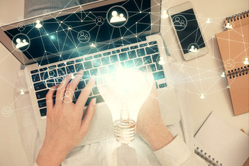 Double exposure of woman hands working on computer and light bulb hologram drawing. Top View. Idea concept.