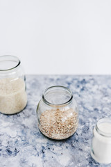 non-perishable food ingredients for vegan pantry, glass jars with oats flour and rice