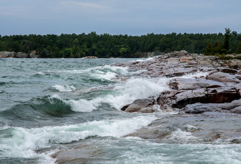 Fototapeta na wymiar Waves slplashing on rocky shoreline Georgian Bay Ontario Canada