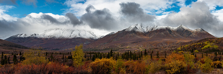 Panorama of Tombstone Territorial Park in Northern Canada, Yukon Territory. Stunning fall in the Yukon Territory with snow capped mountains, yellow, orange landscape panoramic