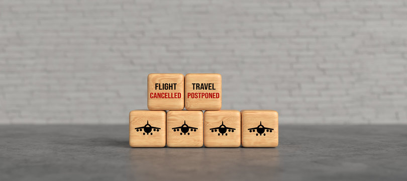 cubes with message FLIGHT CANCELLED, TRAVEL POSTPONED in front of a brick wall