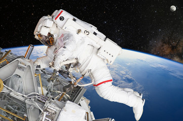 Astronaut on space mission with moon and earth on the background. Elements of this image furnished...