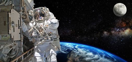Astronaut on space mission with moon and earth on the background. Elements of this image furnished...