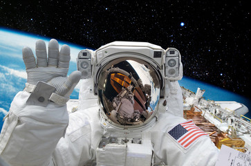 Astronaut on space mission with moon and earth on the background. Elements of this image furnished...