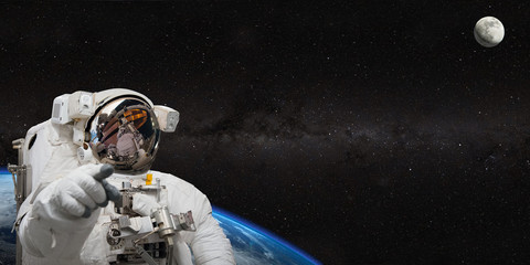 Astronaut on space mission with moon and earth on the background. Elements of this image furnished...