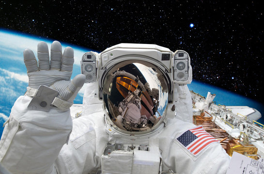 Astronaut on space mission with moon and earth on the background. Elements of this image furnished by NASA.