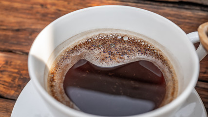 black coffee in white cup on wooden background.