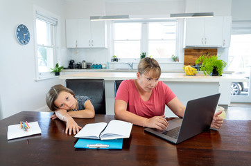 COVID-19 school lockdowns and remote working. Stressed woman working from home with bored daughter