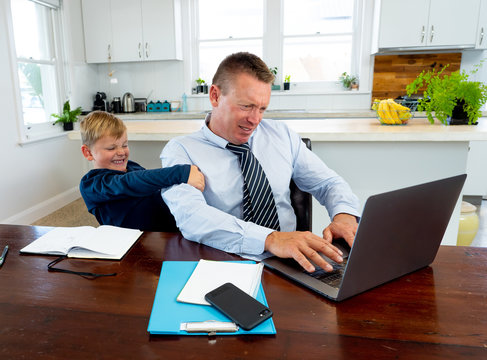 COVID-19 School Lockdowns And Remote Working. Stressed Man Trying To Work From Home With Bored Son