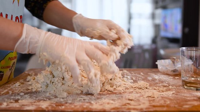 Female hands kneading dough in flour on table