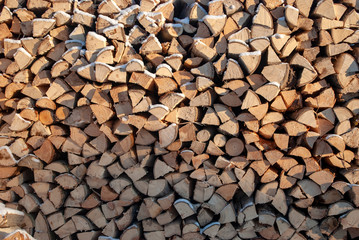 Background texture of stacked firewood. Firewood stacked on top of each other. Harvesting firewood for heating in cold weather.