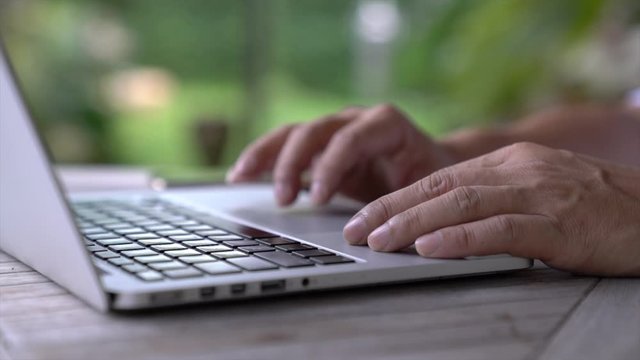 Businessman working on his laptop. Closeup. Garden background. Work remotely or from home concept.