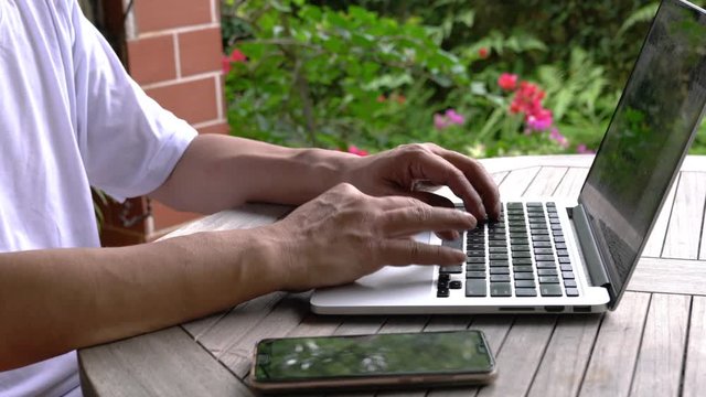 Businessman working on his laptop. Closeup. Garden background. Work remotely or from home concept.