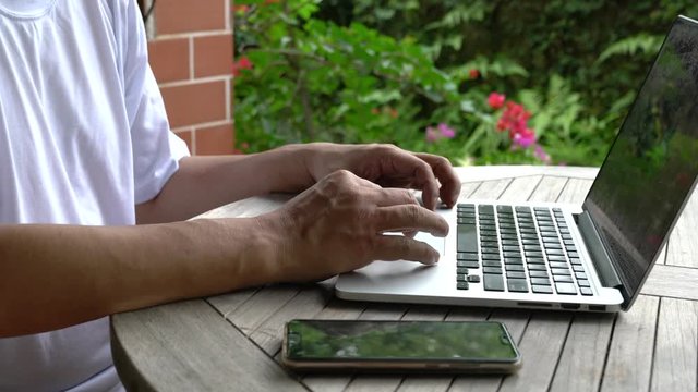 Businessman working on his laptop. Closeup. Garden background. Work remotely or from home concept.