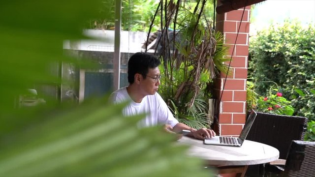 Businessman working on his laptop. Closeup. Garden background. Work remotely or from home concept.