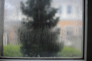 window soaked by rain storm. water droplet caught on transparent glass window. blur image of house on the other side of the street. stay at home while raining and thunderstorm season.