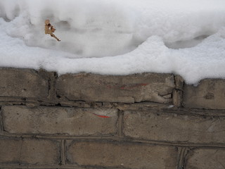 fragment of a gray brick wall with a snow cap
