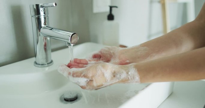 CINEMAGRAPH - seamless loop. Washing hands woman rinsing soap with running water at sink, Coronavirus prevention hand hygiene. Corona Virus pandemic protection cleaning hands.