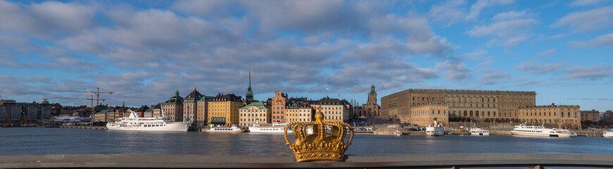 Obraz premium View over the old town district Gamla Stan from the island Skeppsholmen in a sunny spring morning with boats and harbor piers.