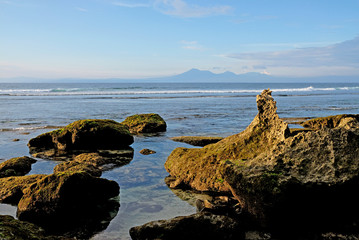 Beautiful coastline with rocks in the foreground and volcanic mountains at the background. A perfect spot for surfers all over the world in Uluwatu, Bali, Indonesia