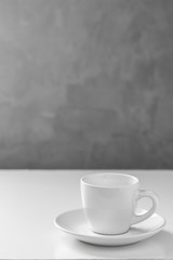 white cup of coffee on white floor and gray wall