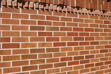 Traditional red and brown brick wall texture background with rows of protruding bricks showing geometric brickwork designs (angle view)