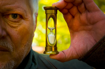 Portrait of an older man. Receives an hourglass in his hand as a symbol for the passing time.
