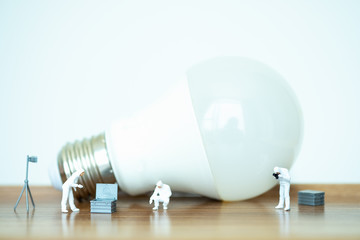 Miniature people: Worker team and lamp with copy space for text using as background saving, investment, money, financial, business analytics concept.