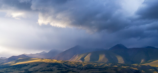 Mountain landscape, panoramic view. Cloudy sky, evening light, severe weather.