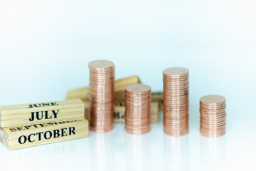 Miniature people: Wooden month and stack of coins with copy space for text using as background saving, investment, money, financial, business analytics concept.