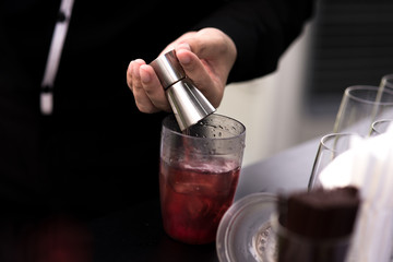 Bartender pouring cocktail in glasses