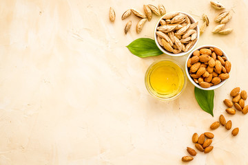Almond oil - for cooking - in glass bowl near nuts on beige background top-down copy space