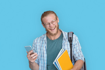 Cheerful young man student hipster blogger glasses hold modern smart phone read text message laugh...
