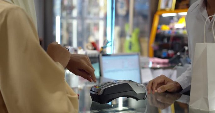 Young woman use smartwatch paying over contactless transactiona at cashier counter