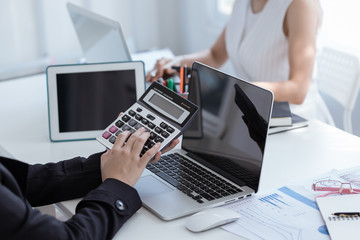 Business woman using a calculator to calculate the numbers on his desk in a office.