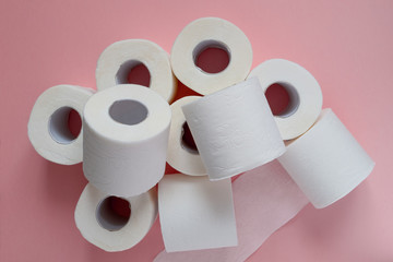 Lots of rolls of white toilet paper on a pink background. Panic, covid-19 concept. Horizontal orientation. View from above.