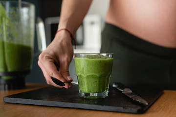 female hand takes a spoon, delicious and healthy smoothie made from natural green herbs and healthy vegetables. Source of energy.