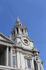 Fototapeta na wymiar Clock tower and statue of Queen Anne at St Paul's Cathedral against blue clear sky, London, UK